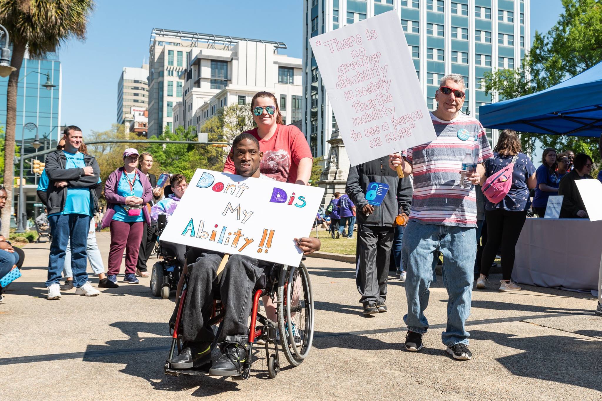 A crowd of diverse people with disabilities hold signs of support for disability rights at the annual Advocacy Day for Access and Independence