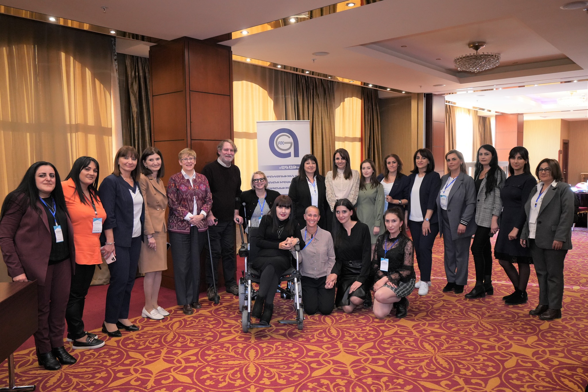 Kimberly, standing with her crutches, surrounded by members of the Armenia Independent Living movement, smiling to the camera.