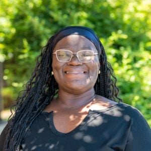 Karmen, a Black woman with glasses and long dark hair wearing a black shirt.